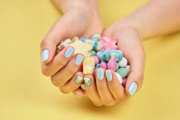 Colorful candies in womans hands.