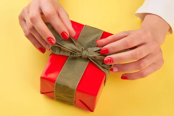 Female hands unpacking red gift box.