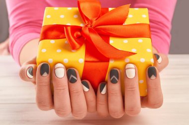 Hediye kutusu holding manikürlü eller.