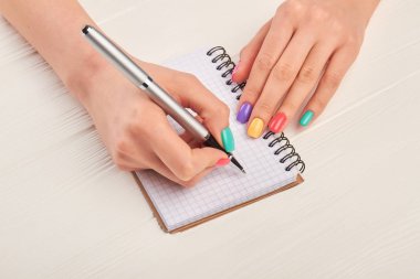 Manikürlü el üstünde defter yazma.