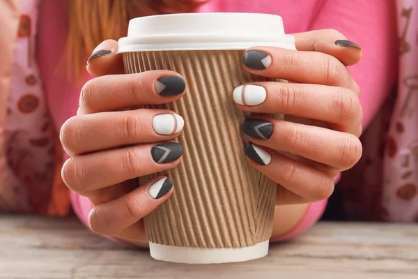 Manicured hands holding cardboard cup. — Stock Photo, Image