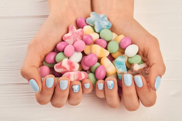 Colorful candies in manicured hands.