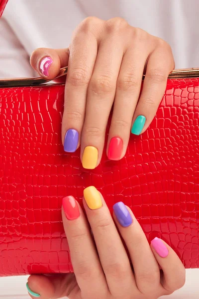 Multicolored nails and red leather handbag. — Stock Photo, Image