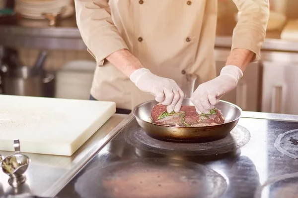 Шеф-повар кладет мясо на сковородку . — стоковое фото