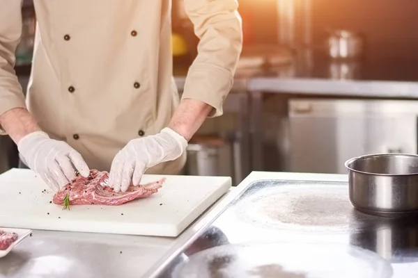 Chef macho cocinando costillas de cordero . — Foto de Stock