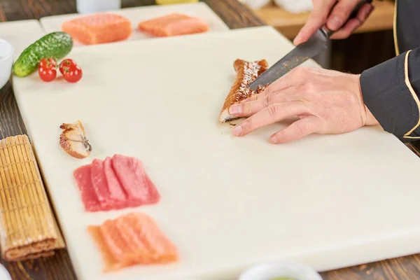 Chef-kok handen met mes snijden gerookte paling. — Stockfoto