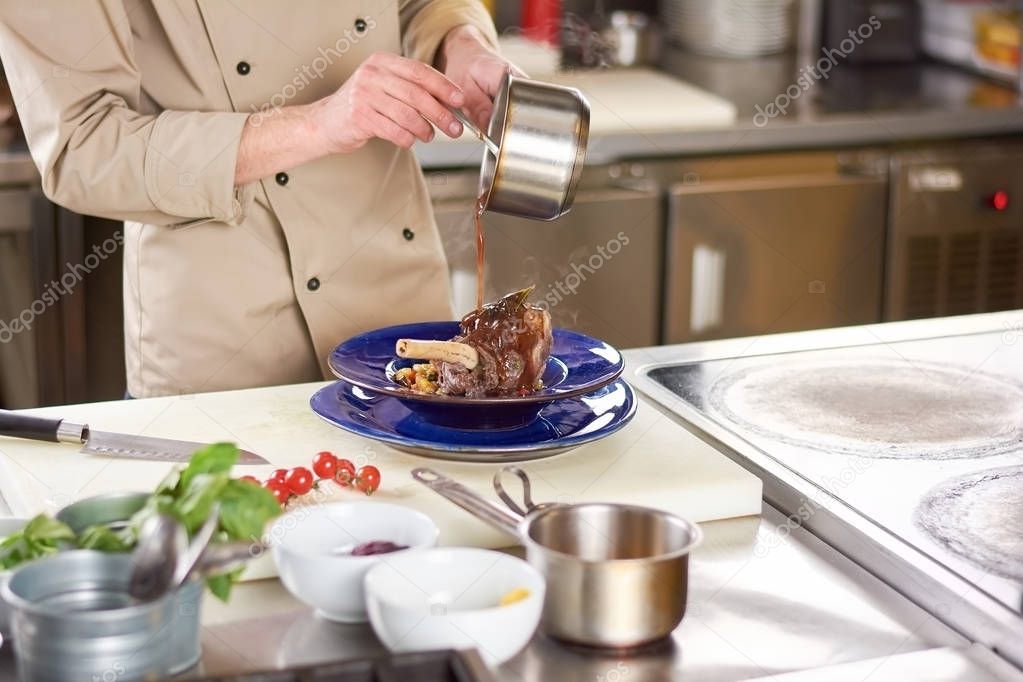 Chef pouring sauce on lamb shank.
