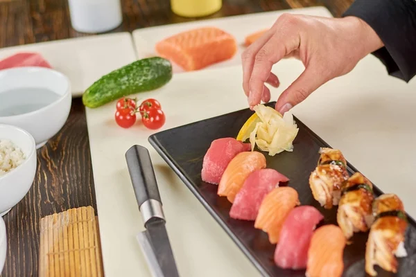 Chef agregando jengibre al sushi en el plato . — Foto de Stock