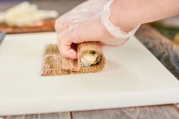 Laga mat i engångshandskar att göra sushi rulle. — Stockfoto