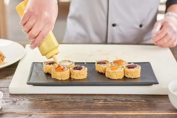 Chef vertiendo sushi con salsa . — Foto de Stock