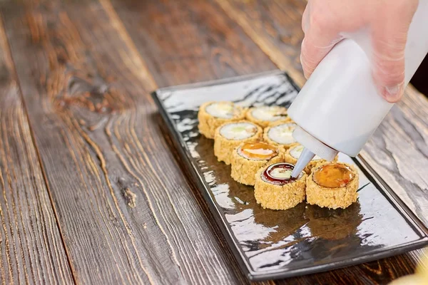 Kocken hälla sushi rulle med sås. — Stockfoto