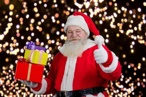 Papai Noel com presentes mostrando polegar para cima . — Fotografia de Stock