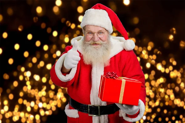 Papai Noel com presente dando polegar para cima . — Fotografia de Stock