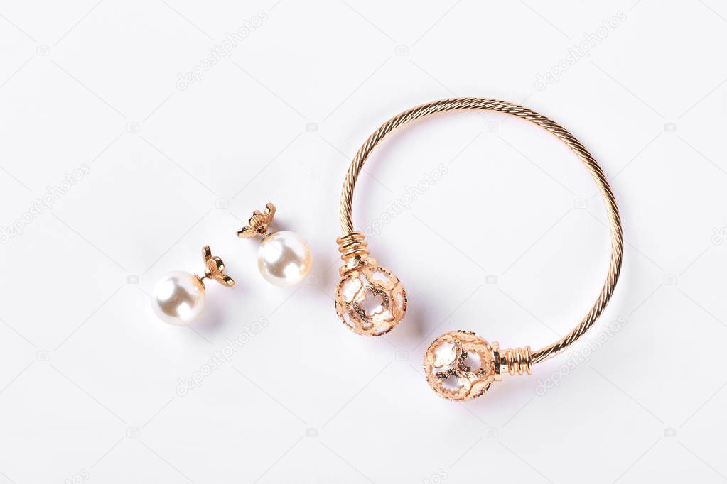 Female earings and bracelet on white background.