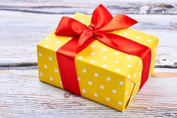 Κίτρινο δώρο κουτί με κόκκινη κορδέλα. — Φωτογραφία Αρχείου