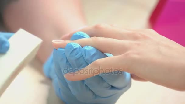 Косметик в перчатках полирует ногти для клиента . — стоковое видео