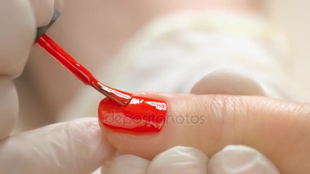 Close up manicurist applying red varnish. — Stock Video