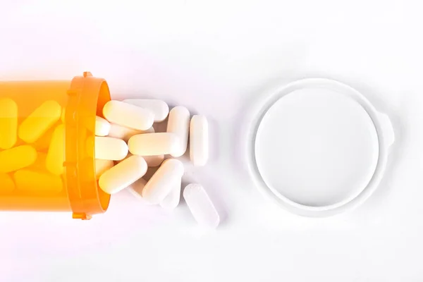 Pills spilling out from yellow container. — Stock Photo, Image