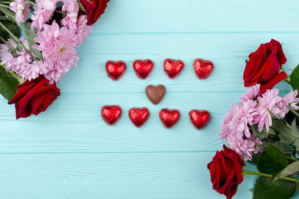 Όμορφα λουλούδια και σοκολάτα σε σχήμα καρδιάς. — Φωτογραφία Αρχείου