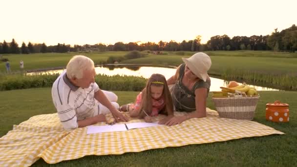 Abuelos dibujo con nieta al aire libre . — Vídeo de stock