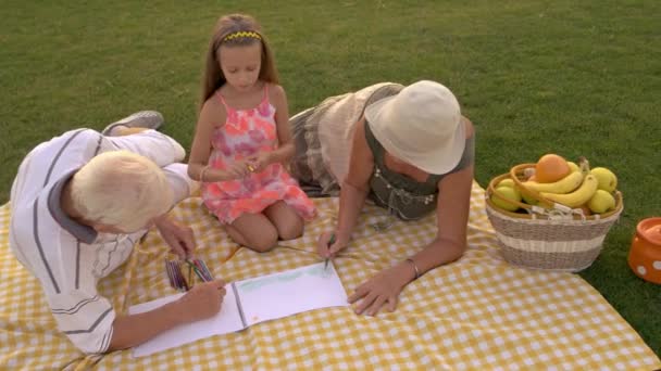 Seniors and child drawing together outdoors. — Stock Video