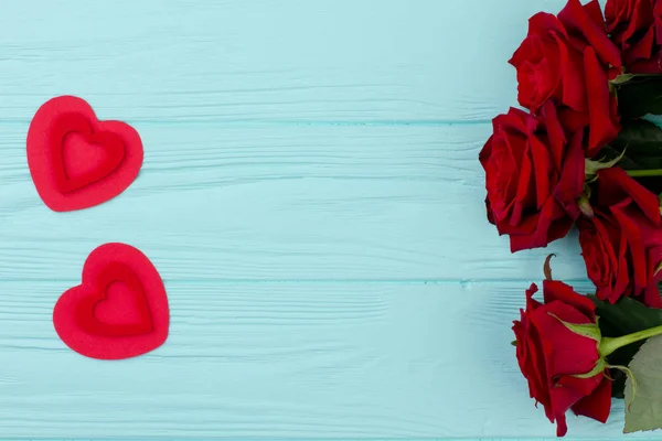Rosas vermelhas com corações na mesa de madeira . — Fotografia de Stock