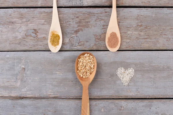 Spoons and cereals on wooden background.