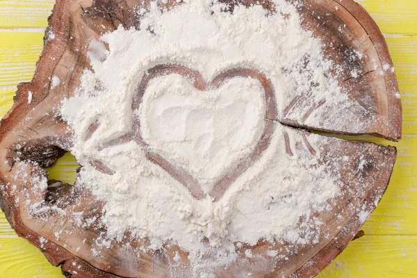 Shape of heart drawn on white flour.