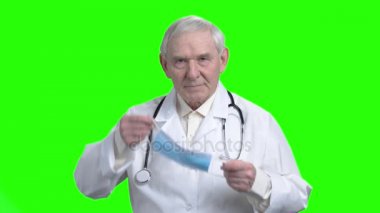 Yaşlı doktor tıbbi maske üzerine koyarak.