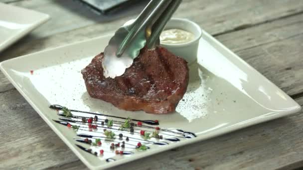 Pinzas que ponen comida en el plato . — Vídeos de Stock