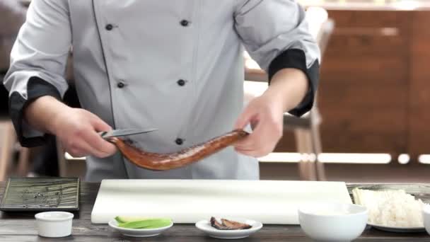 Sushi chef cutting smoked eel. — Stock Video