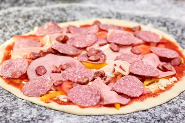 Çiğ pizza birçok dilimlenmiş sosis ile yakın çekim.