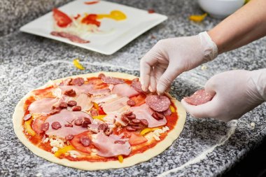 Şef pişirme salamlı pizza.