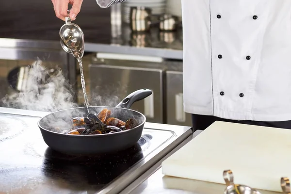 Kocken hälla ättika på pannan med musslor. — Stockfoto