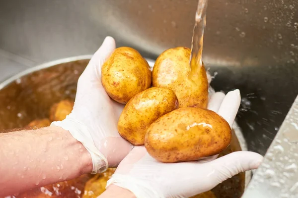 Čtyři brambory mytí pod tekoucí vodou. — Stock fotografie