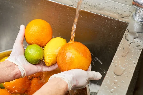 Citrusvruchten assortiment wassen in een leidingwater. — Stockfoto