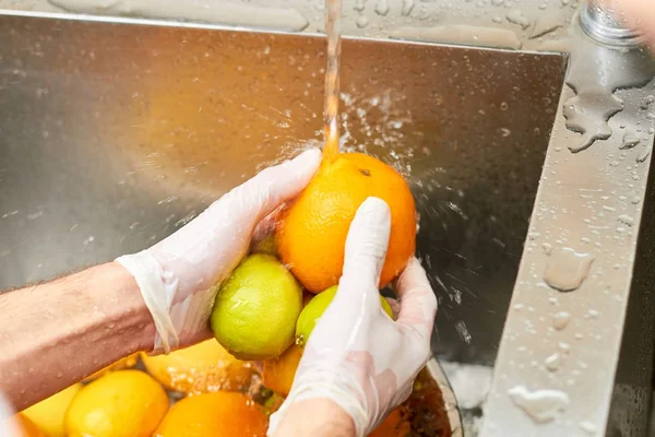 Kuchař, mytí citrusových plodů v dřezu. — Stock fotografie