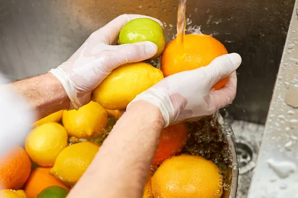 Pomeranč, citron a vápno v rukou šéfkuchař oplachovací voda z kohoutku za mokra. — Stock fotografie