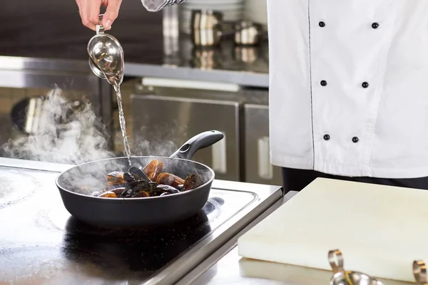 Chef pouring vinegar on pan with mussels. Royalty Free Stock Photos