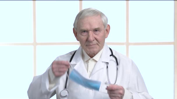 Retrato del médico anciano se puso una máscara médica azul protectora . — Vídeo de stock