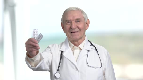Alter Oberarzt mit zwei Päckchen Pillen und Daumen hoch. — Stockvideo