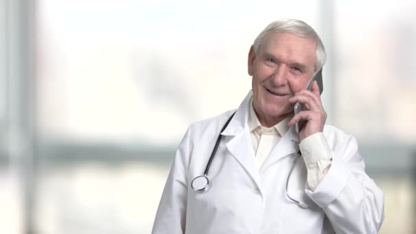 Positiv glad senior doktor talar i telefon. — Stockvideo