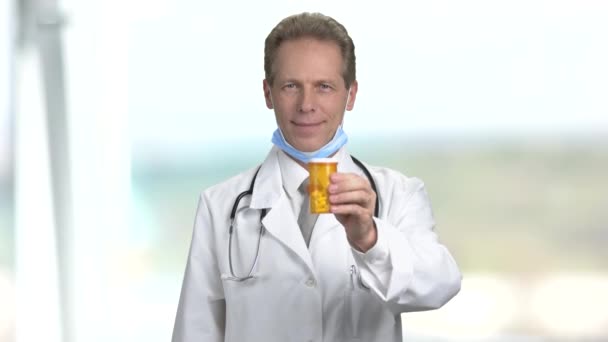 Mature smiling doctor offers can of pills. — Stock Video