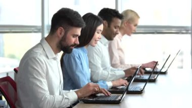 Ofiste oturan ve dizüstü bilgisayarlarda çalışan insanlar.