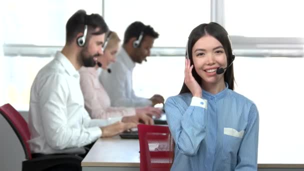 Glada asiatisk tjej i callcenter med headsetet godkänner. — Stockvideo