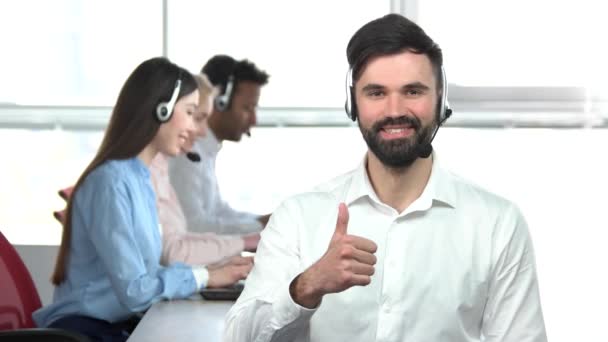 Jeune homme beau avec la barbe montrant pouce au bureau . — Video