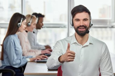 Başparmak ile beyaz sakallı adam parlak ofiste gülümseyen.