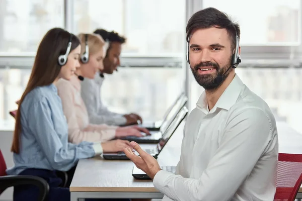 Kaukasischer junger Mann zeigt auf seine Kollegen im Callcenter. — Stockfoto