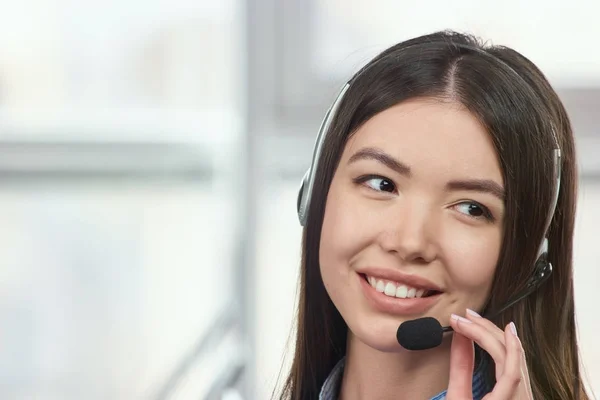 Recepcionista amigable sonriendo y usando un auricular . — Foto de Stock