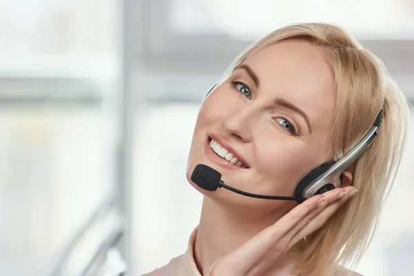 Mujer rubia madura sosteniendo auriculares . — Foto de Stock